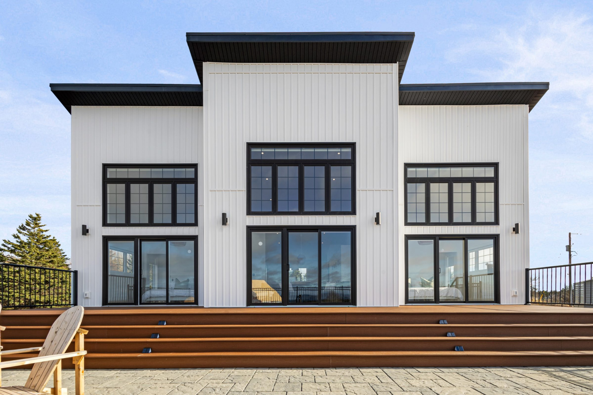 Modern dark-clad beach house with floor-to-ceiling windows on a rocky Nova Scotia shoreline